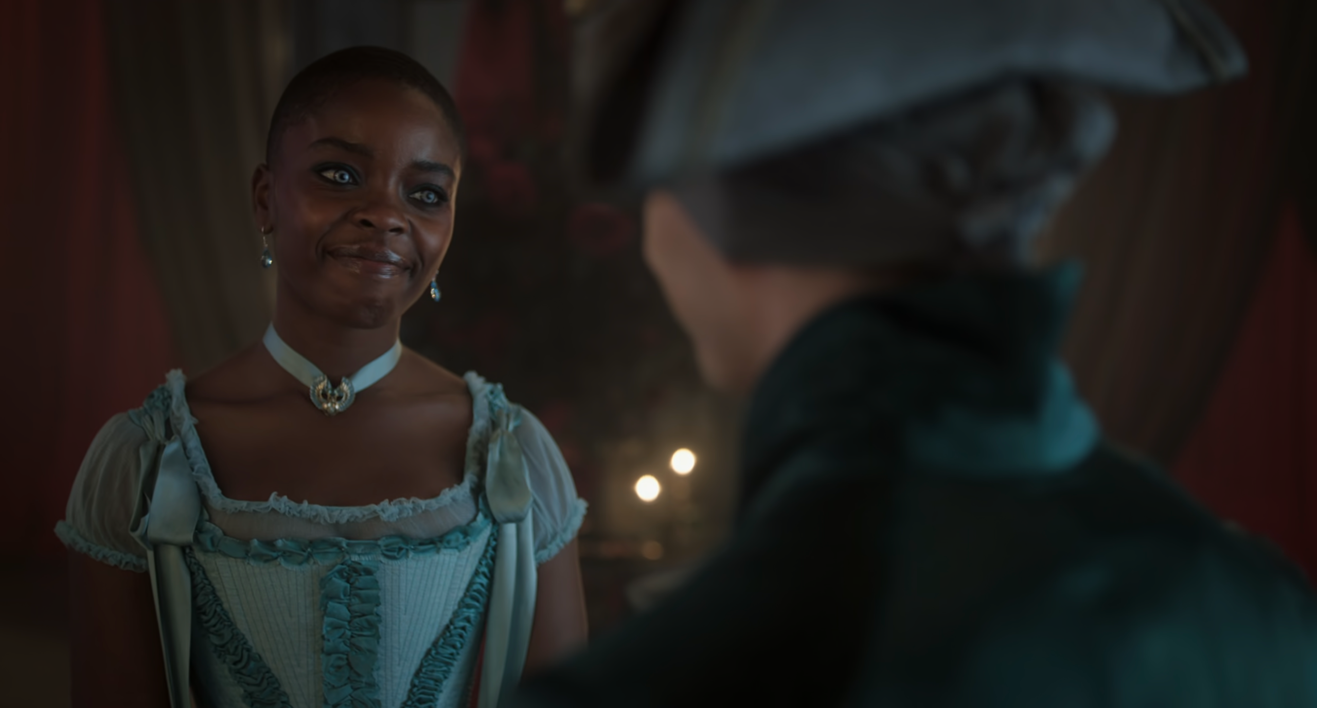 Bianca Barclay smiling warmly at Ajax Petropolus after the gala. She is wearing an elegant light blue period-style gown with a jeweled choker, under soft, candlelit lighting.