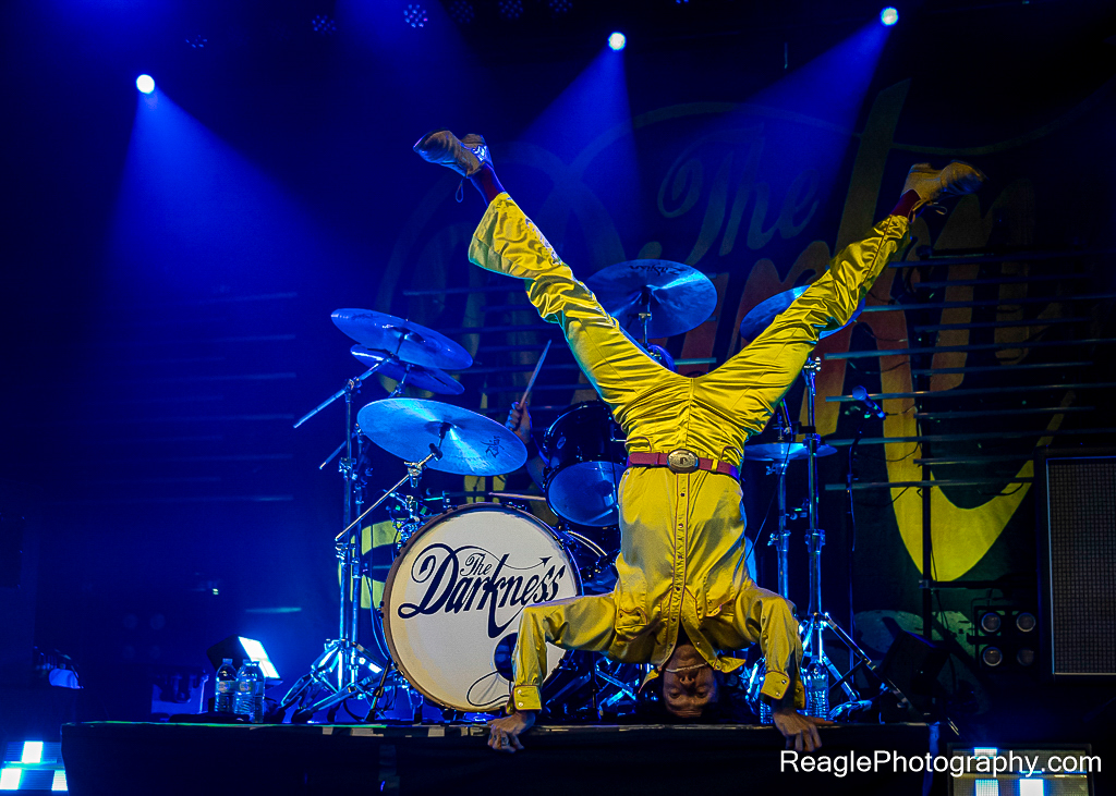 Justin Hawkins of The Darkness doing a headstand in front of their drum kit