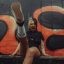 Alternative punk artist MEGG kicking toward the camera in front of graffiti wall