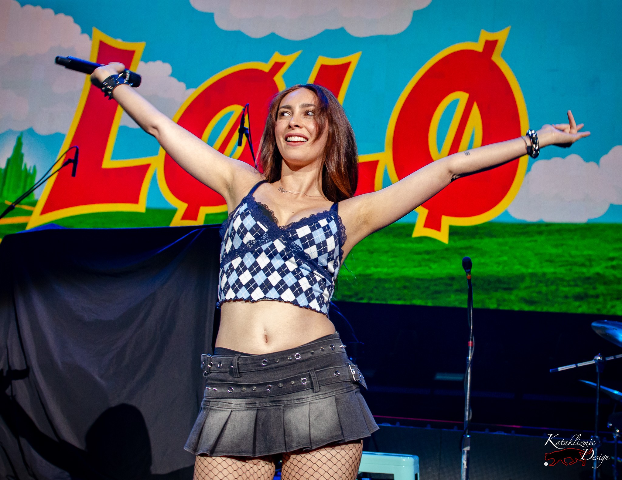 LØLØ sings with arms wide open, smiling brightly at the crowd during her live set.