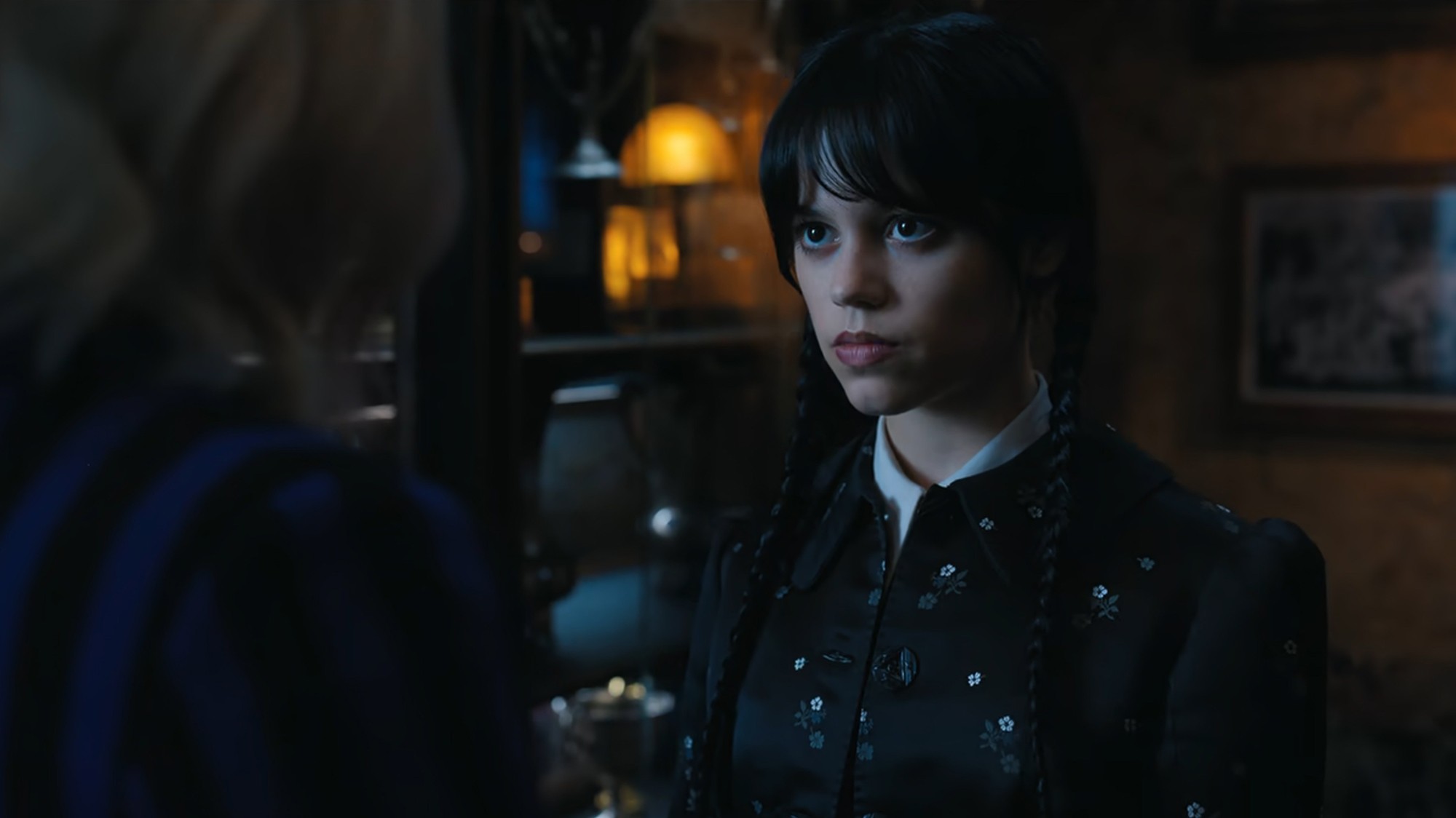 Wednesday Addams in sharp focus while Enid Sinclair is blurred in the background in Netflix’s "Wednesday," using depth-of-field to emphasize Wednesday’s perspective.