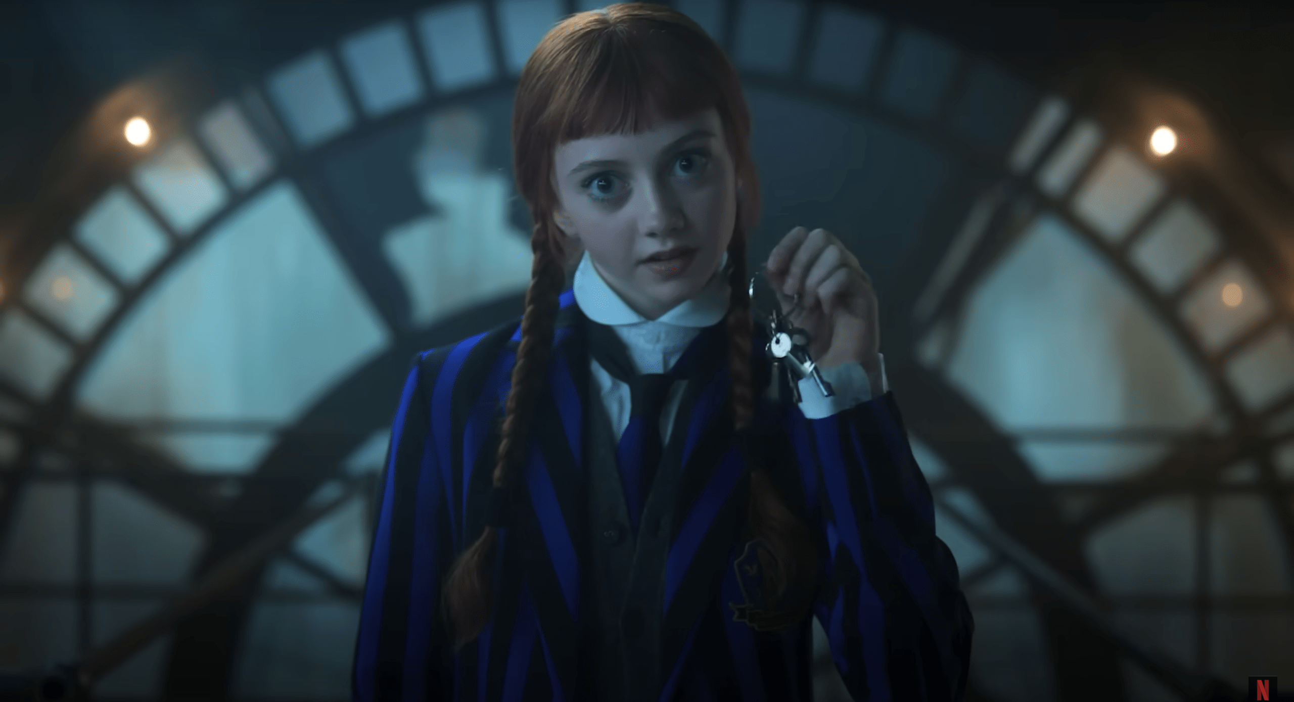 Agnes DeMille in Wednesday Season 2, holding keys while standing in front of the clock tower’s gears.