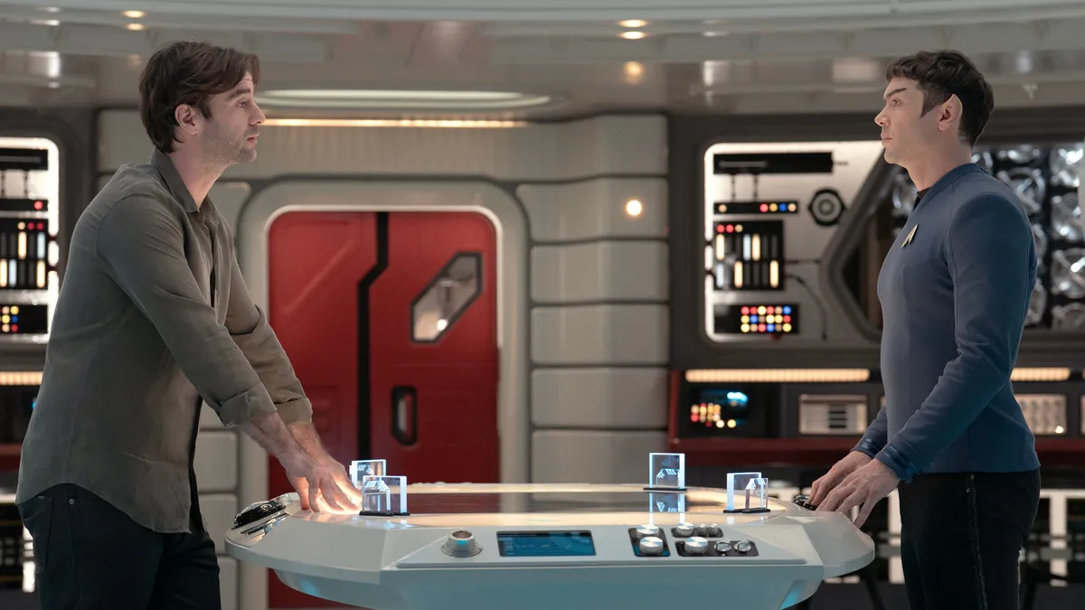 Roger Korby and Spock stand across from each other at a table aboard the Enterprise in Star Trek: Strange New Worlds