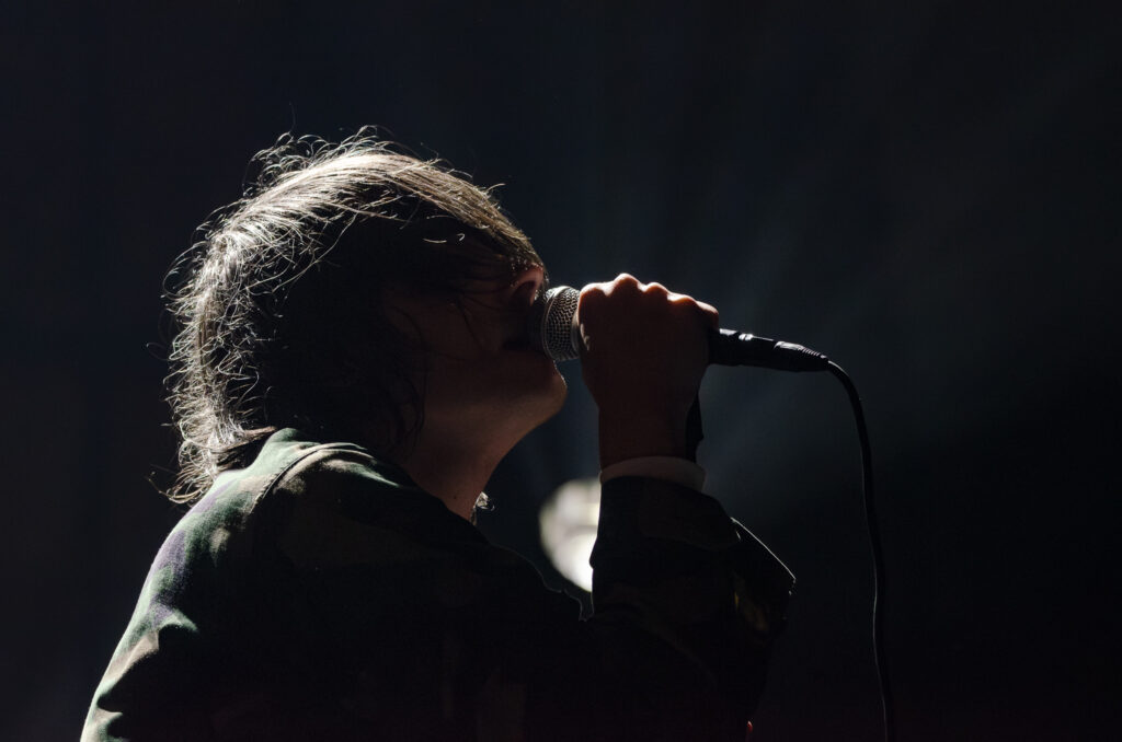 Side profile of Gerard Way of Chemical Romance singing live in partial silhouette