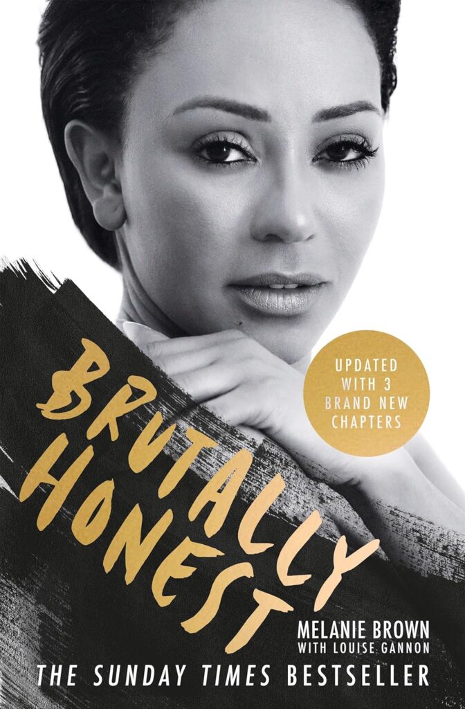 Cover of Brutally Honest by Melanie Brown (Mel B), featuring a black-and-white close-up of the singer with her head resting on her folded hands. She gazes directly at the camera with a calm but intense expression. The title "Brutally Honest" appears in bold, gold handwritten-style lettering across a textured black paint stroke in the bottom left. A gold circle notes “Updated with 3 brand new chapters.”
