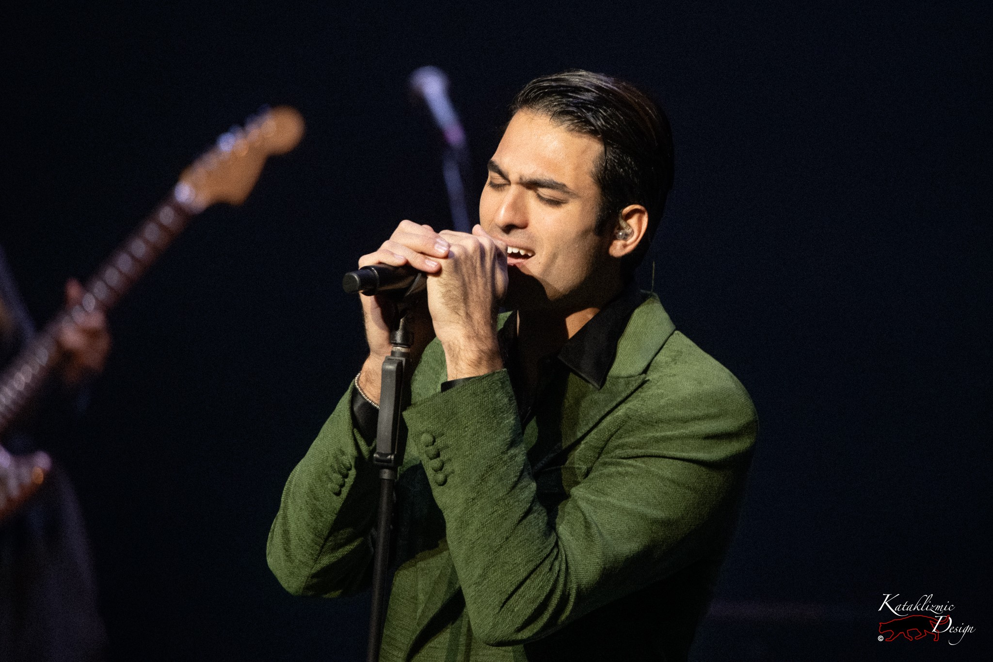 Matteo Bocelli singing with eyes closed, gripping the mic stand during his Mesa concert.