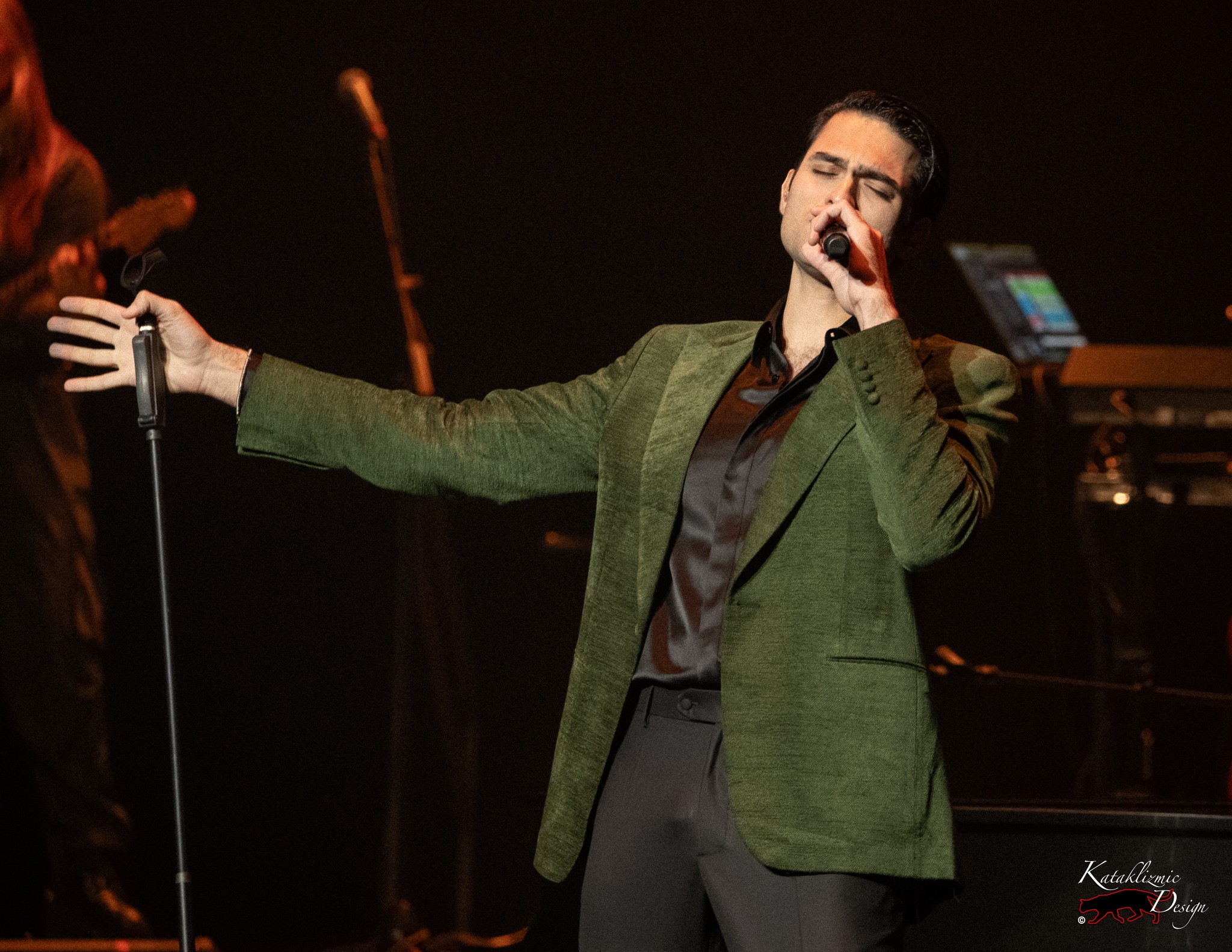 Matteo Bocelli singing passionately with one arm extended on stage.