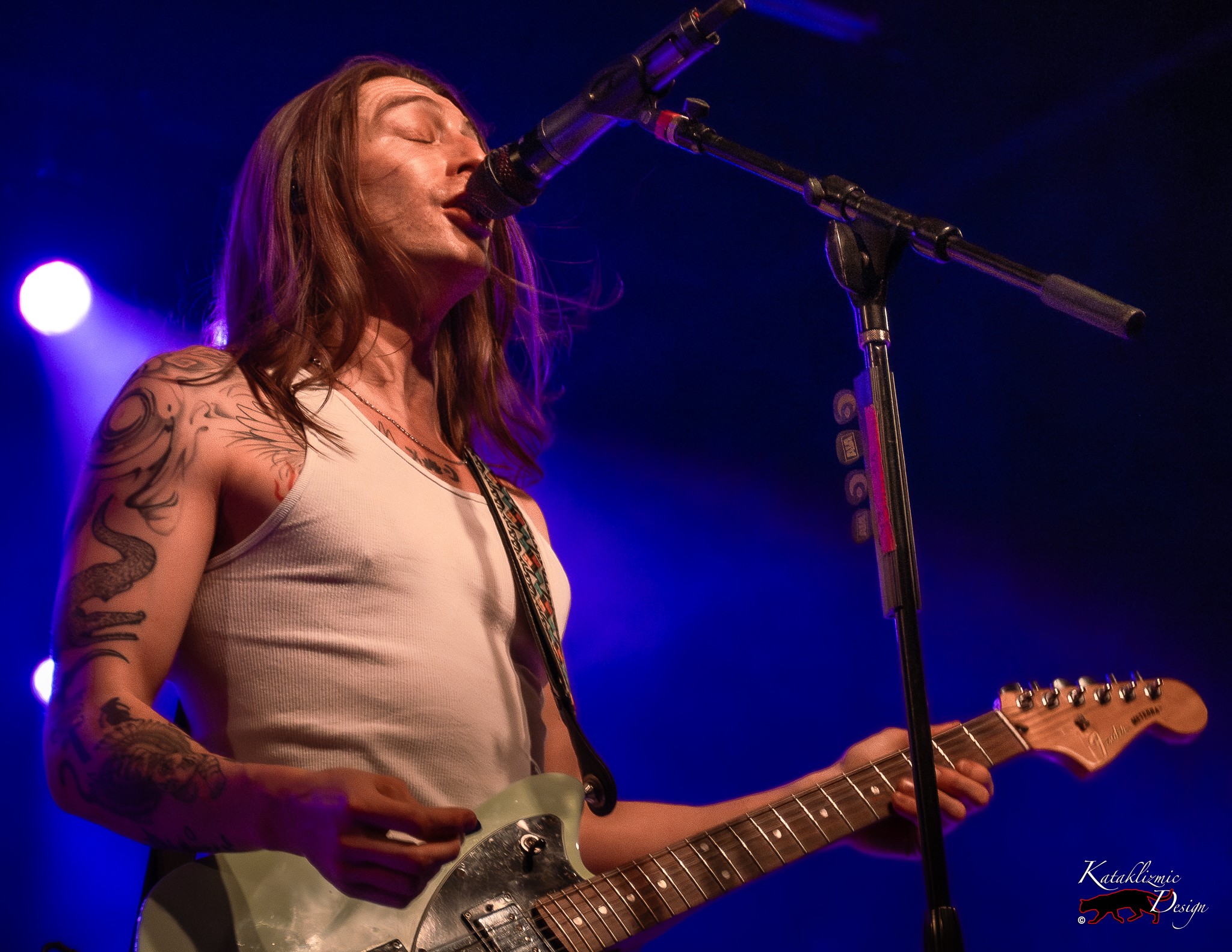 Victor Viramontes-Pattison sings into the microphone while playing guitar during Arrows in Action’s Tempe performance.