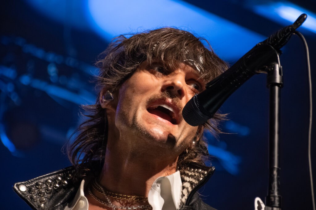BOYS LIKE GIRLS lead singer Martin Johnson performing at Marquee Theatre, singing into a microphone under blue stage lights.