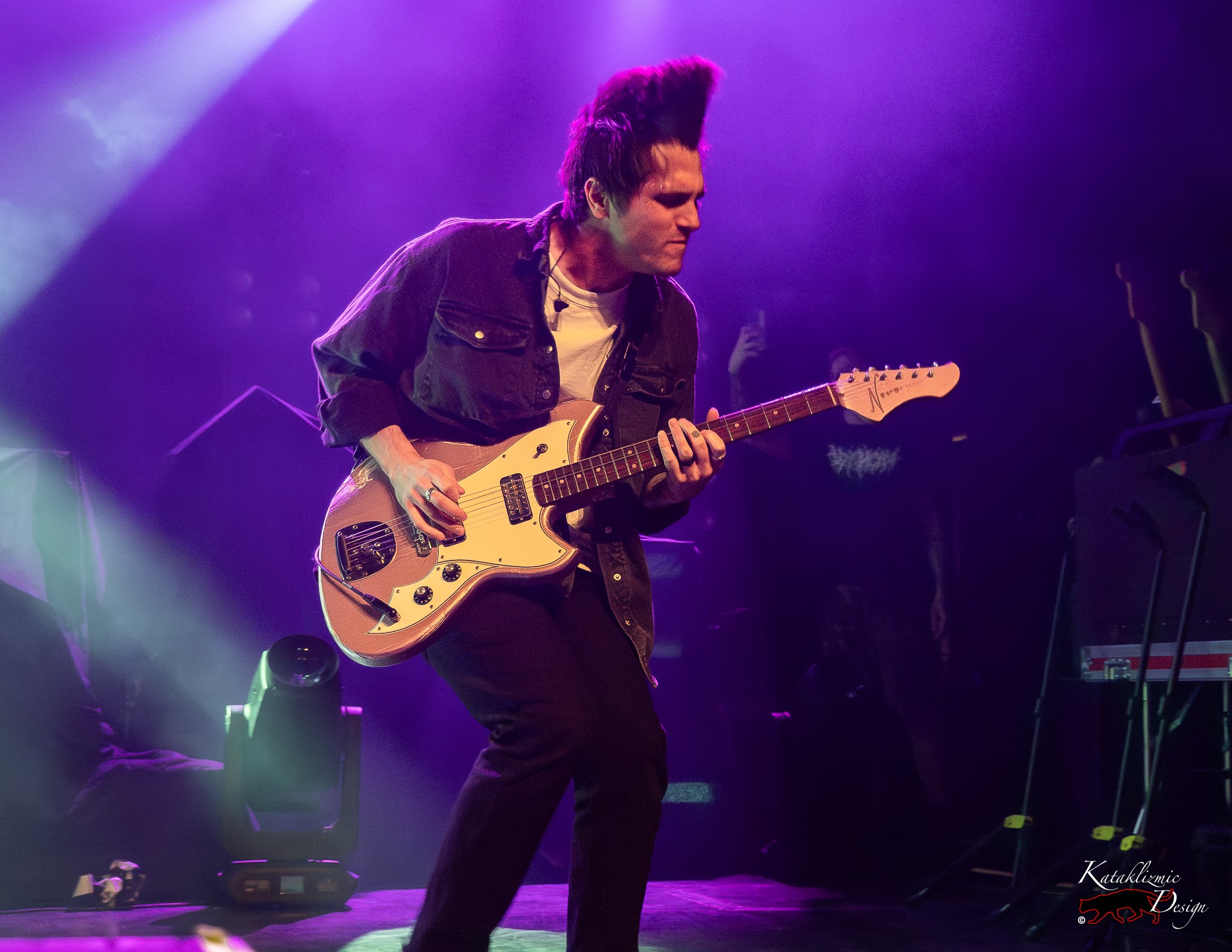 iDKHOW guitarist Anthony Purpura performs under purple and green stage lights during the band’s set.