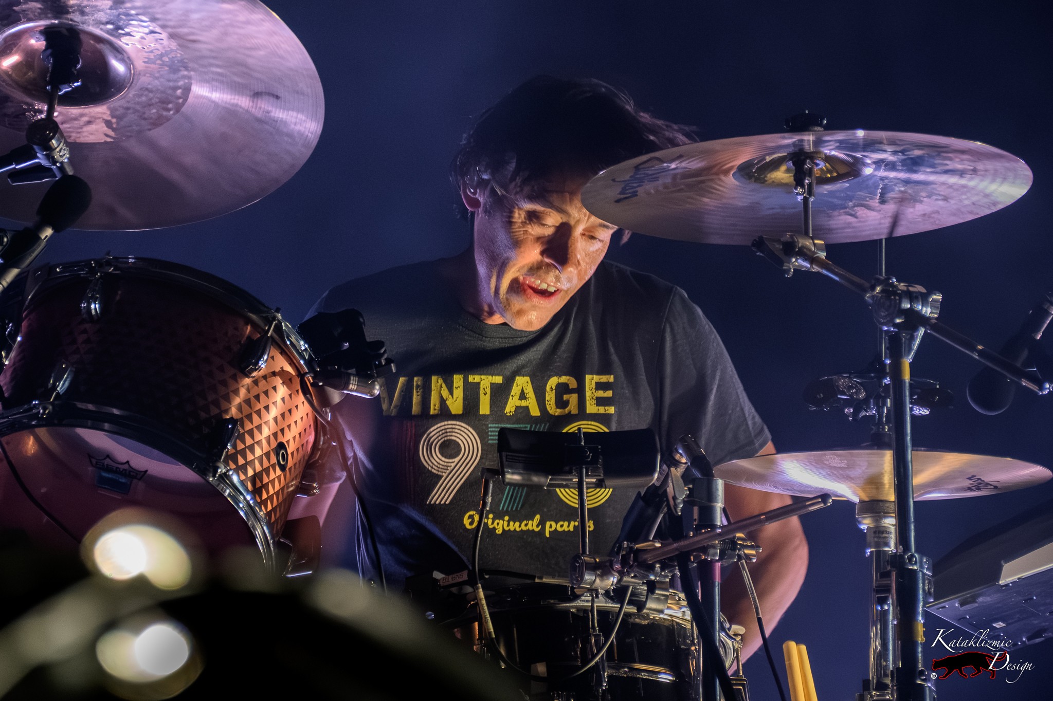 Joules Scott-Key of Metric plays drums surrounded by cymbals and purple stage lighting.