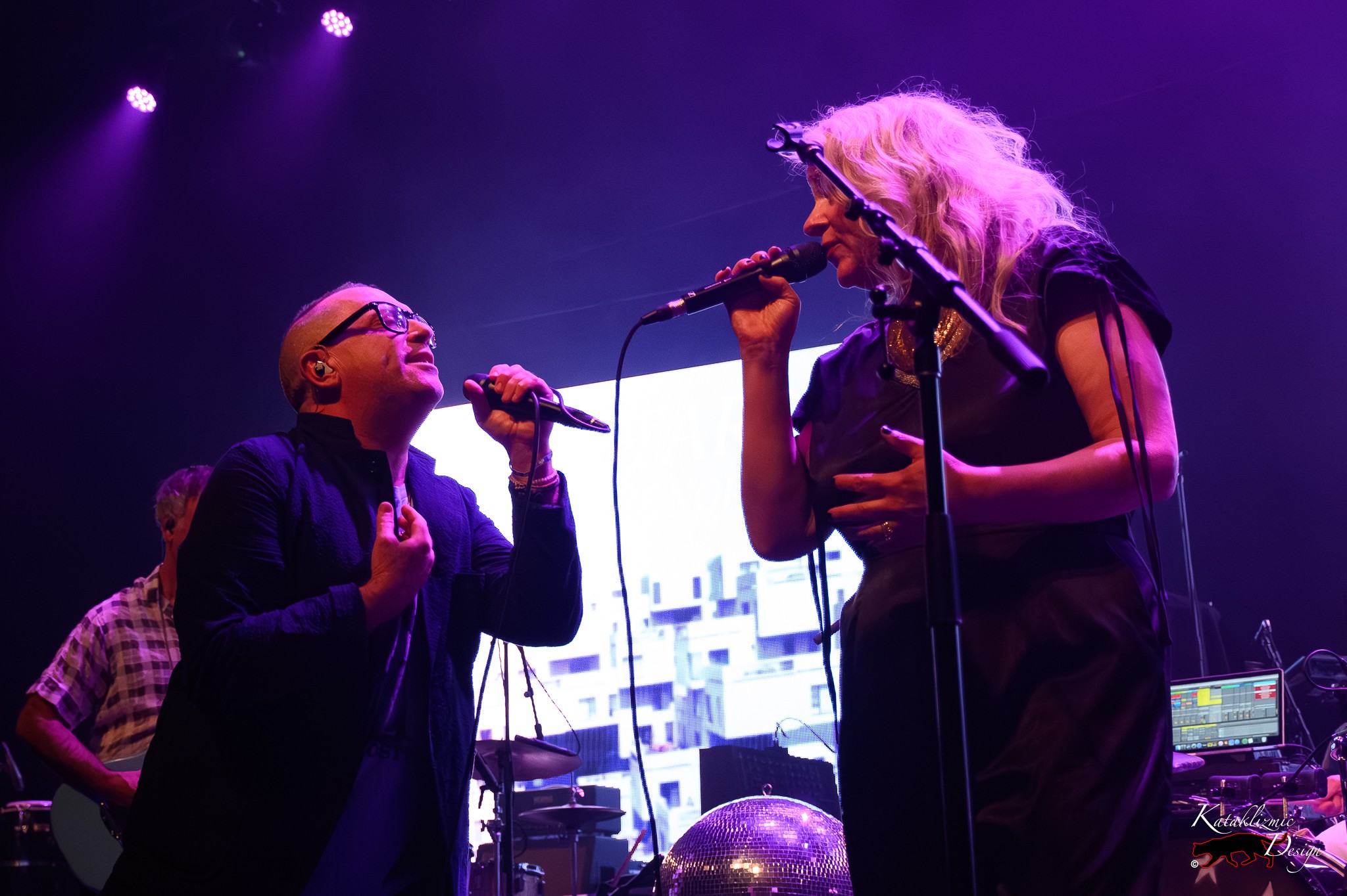 Torquil Campbell and Amy Millan of Stars sing toward each other onstage under purple lighting.