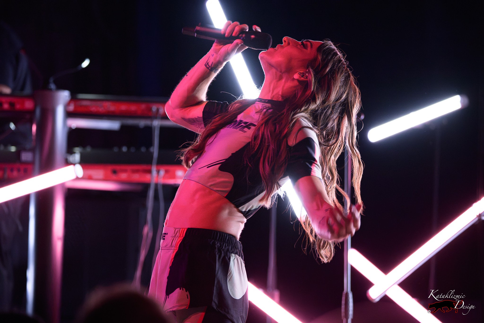Melanie C arches backward while singing beneath pink and white stage lights during The Melanie C World Tour at House of Blues San Diego.