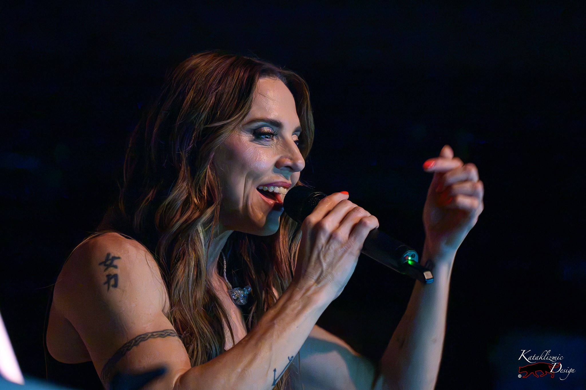 Melanie C smiles while singing into a handheld microphone during The Melanie C World Tour at House of Blues San Diego.