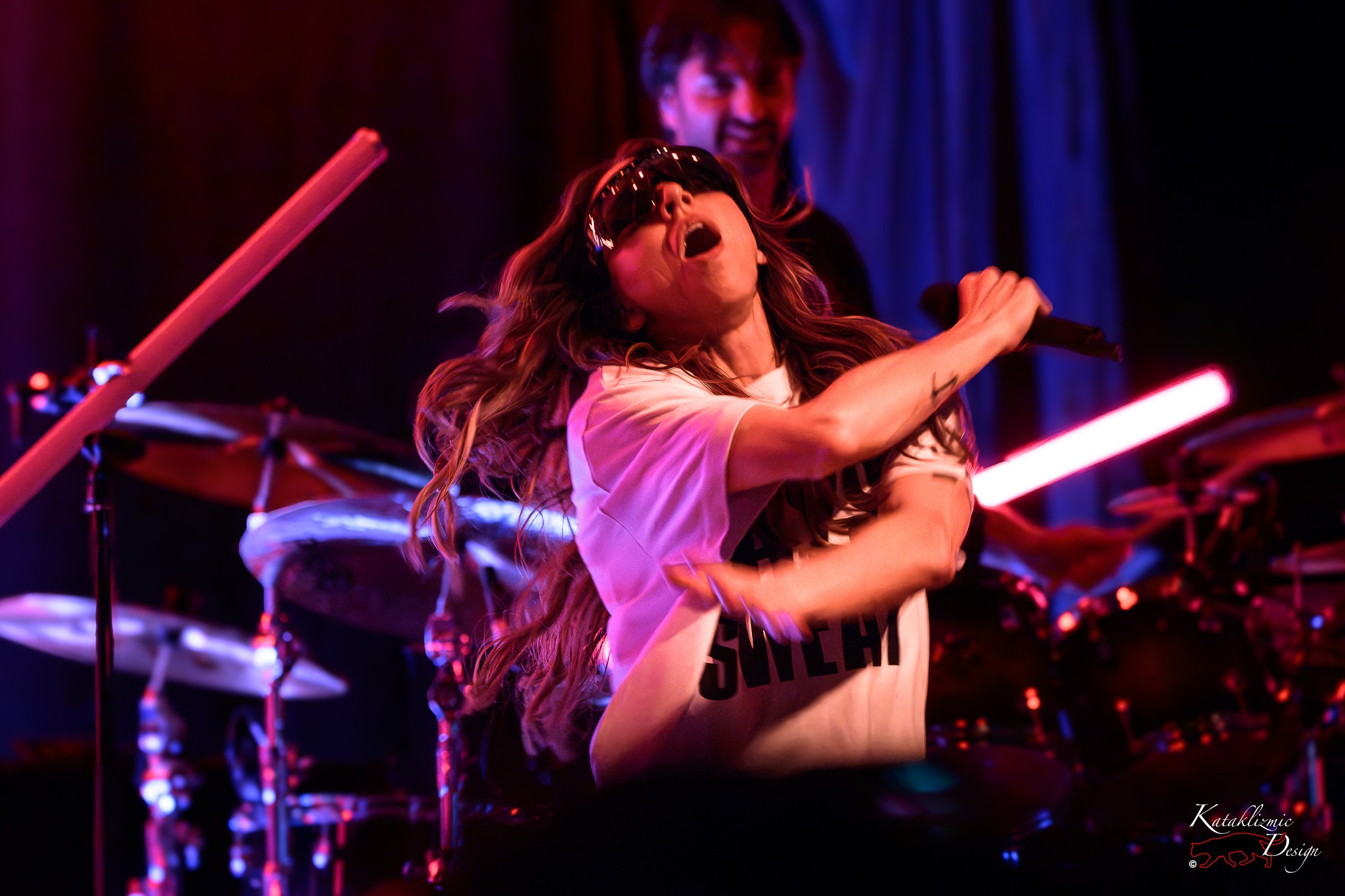 Melanie C performs onstage in a “Sweat” shirt, moving with the music under colorful concert lights.