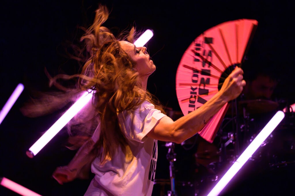Melanie C whips her hair while holding a bright pink fan during The Melanie C World Tour at House of Blues San Diego.