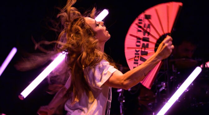 Melanie C whips her hair while holding a bright pink fan during The Melanie C World Tour at House of Blues San Diego.